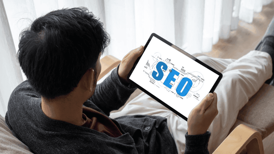 Person holding a tablet displaying the word 'SEO' with diagrams, focusing on SEO Marketing.